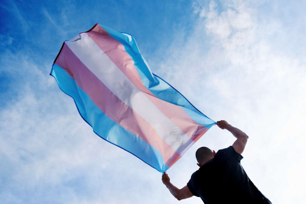 homem transgênero segurando bandeira trans