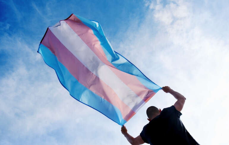 homem transgênero segurando bandeira trans